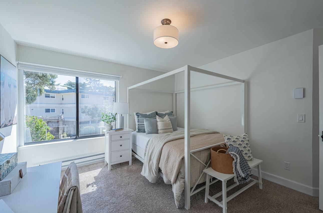 125 Surf Way, Unit 438 Monterey, CA 93940 - Photo 32 of 45 a bedroom with a bed and a large window