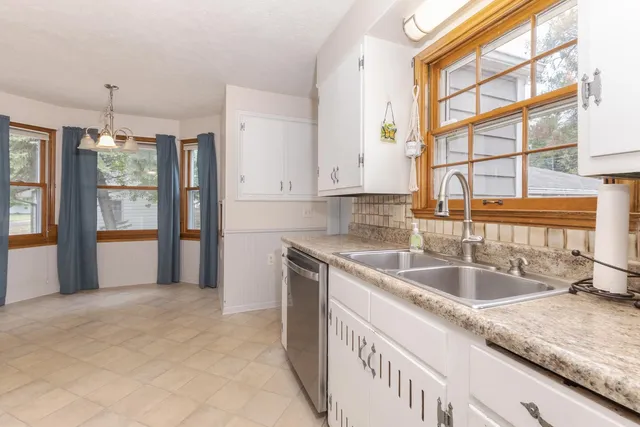 an empty room with chandelier fan and windows
