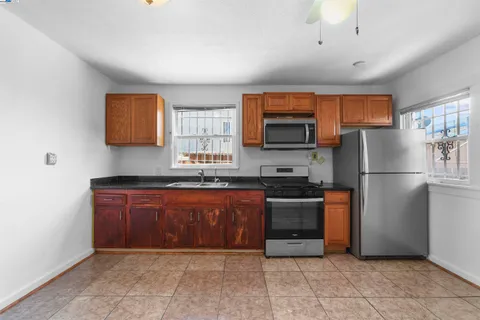 a kitchen with granite countertop a refrigerator and a stove top oven