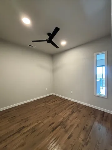 a view of empty room with wooden floor and fan