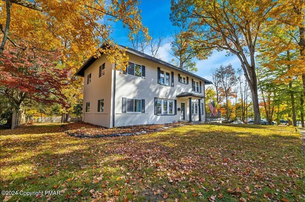 a view of a large white house with a big yard and large trees