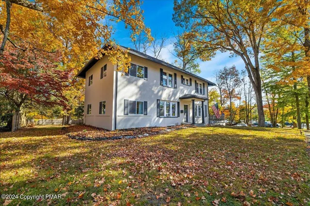 a view of a large white house with a big yard and large trees