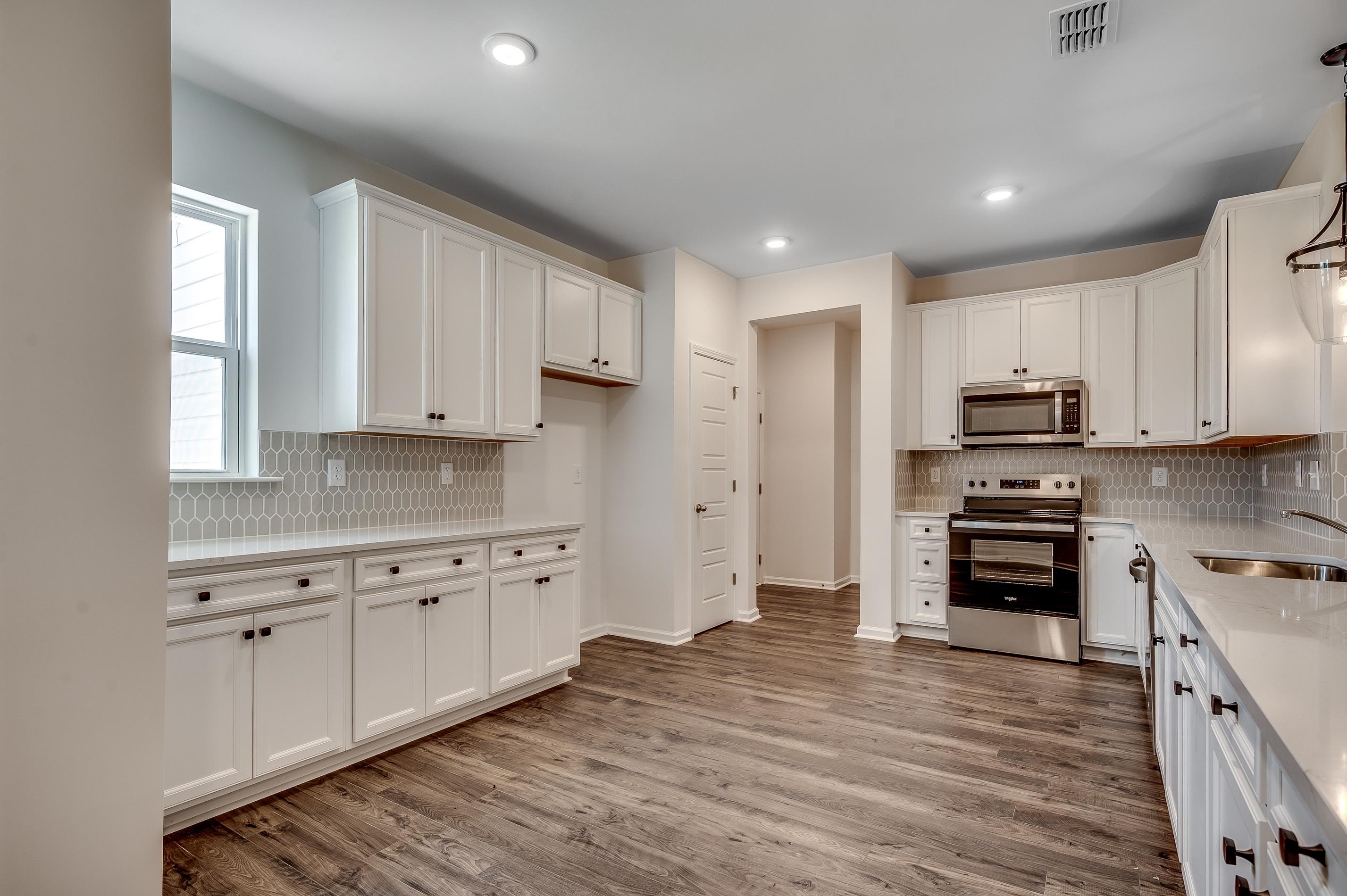 124 Buckingham Drive Loris, SC 29569 - Photo 7 of 17 Kitchen with appliances with stainless steel finishes, white cabinets, light stone countertops, light wood finished floors, and backsplash