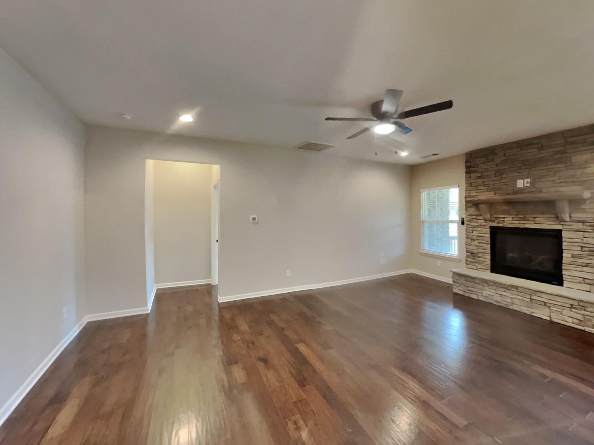 132 Hackney Lane Gallatin, TN 37066 - Photo 2 of 23 an empty room with wooden floor a ceiling fan a fireplace and windows