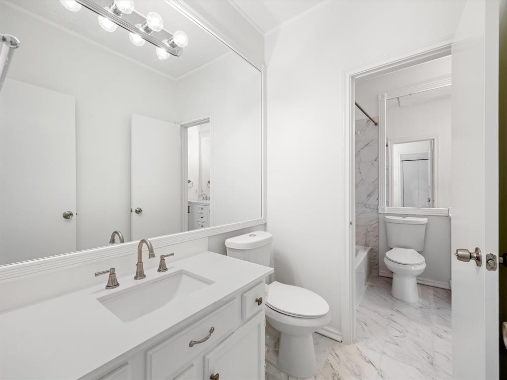 5310 Keller Springs Road, Unit 332 Dallas, TX 75248 - Photo 28 of 38 a bathroom with a toilet a sink a mirror and vanity