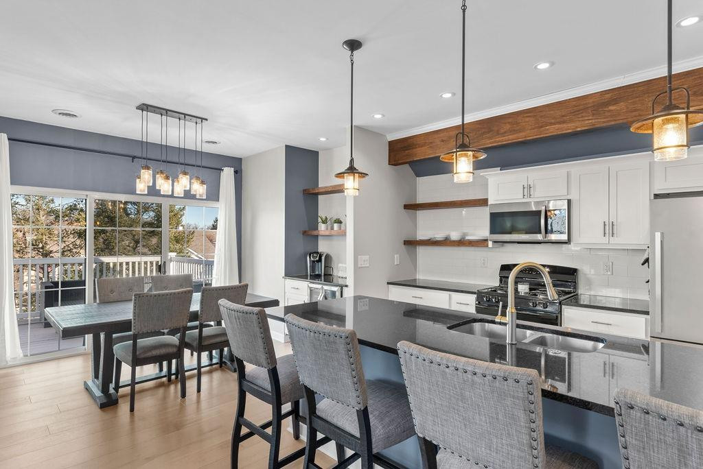 21 B Edinburgh Street Valparaiso, IN 46385 - Photo 4 of 17 a kitchen with stainless steel appliances granite countertop a stove a sink dishwasher a dining table and chairs with wooden floor