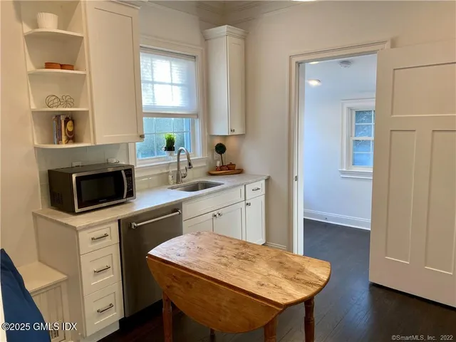 a kitchen with a sink a stove cabinets and wooden floor