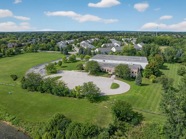 an aerial view of a residential houses with outdoor space and trees all around