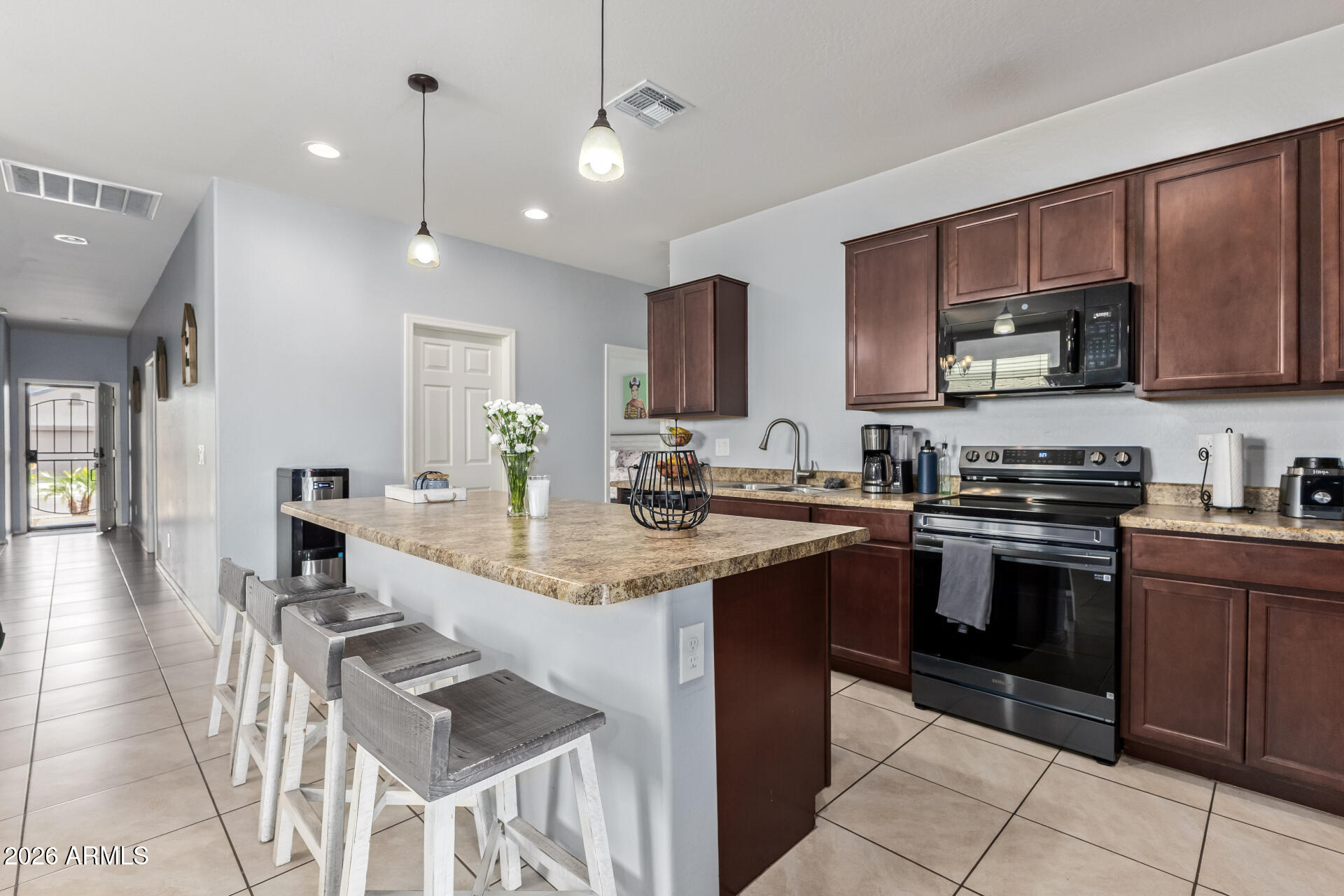10326 West Payson Road Tolleson, AZ 85353 - Photo 12 of 27 a kitchen with stainless steel appliances granite countertop a stove top oven a sink dishwasher a dining table and chairs