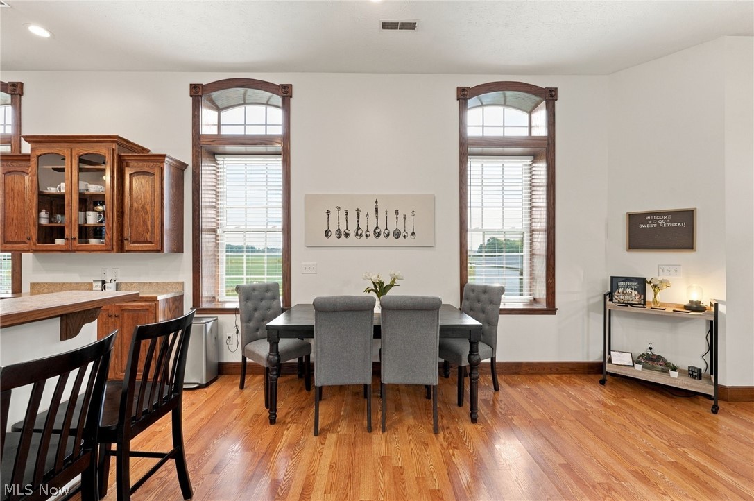 42764 Russia Road Elyria, OH 44035 - Photo 12 of 50 Hardwood flooring, arched windows with wooden trim, built-in cabinetry with glass fronts, and a two-tiered kitchen island