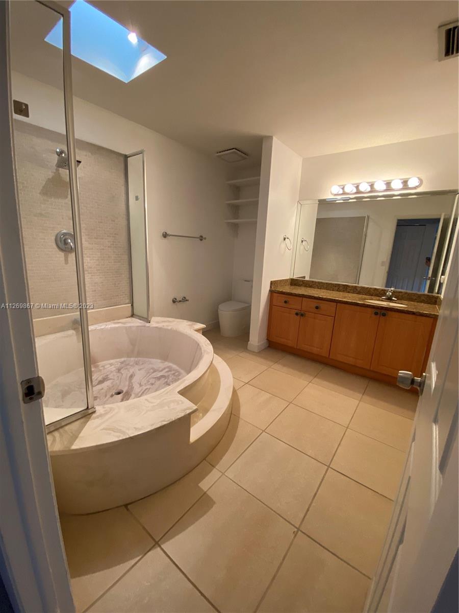 6934 Southwest 114th Place, Unit F55 Miami, FL 33173 - Photo 7 of 10 a bathroom with a tub a sink and mirror