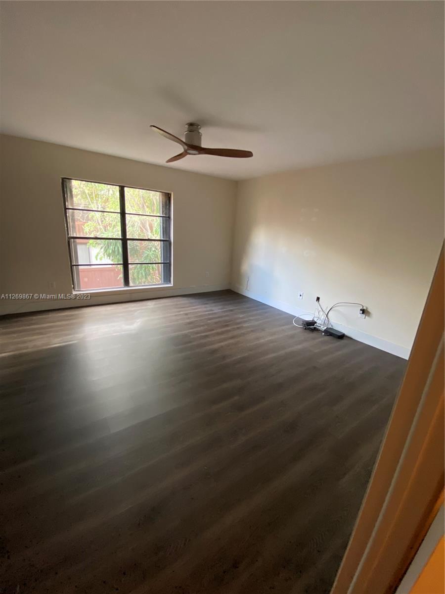 6934 Southwest 114th Place, Unit F55 Miami, FL 33173 - Photo 8 of 10 an empty room with wooden floor and windows
