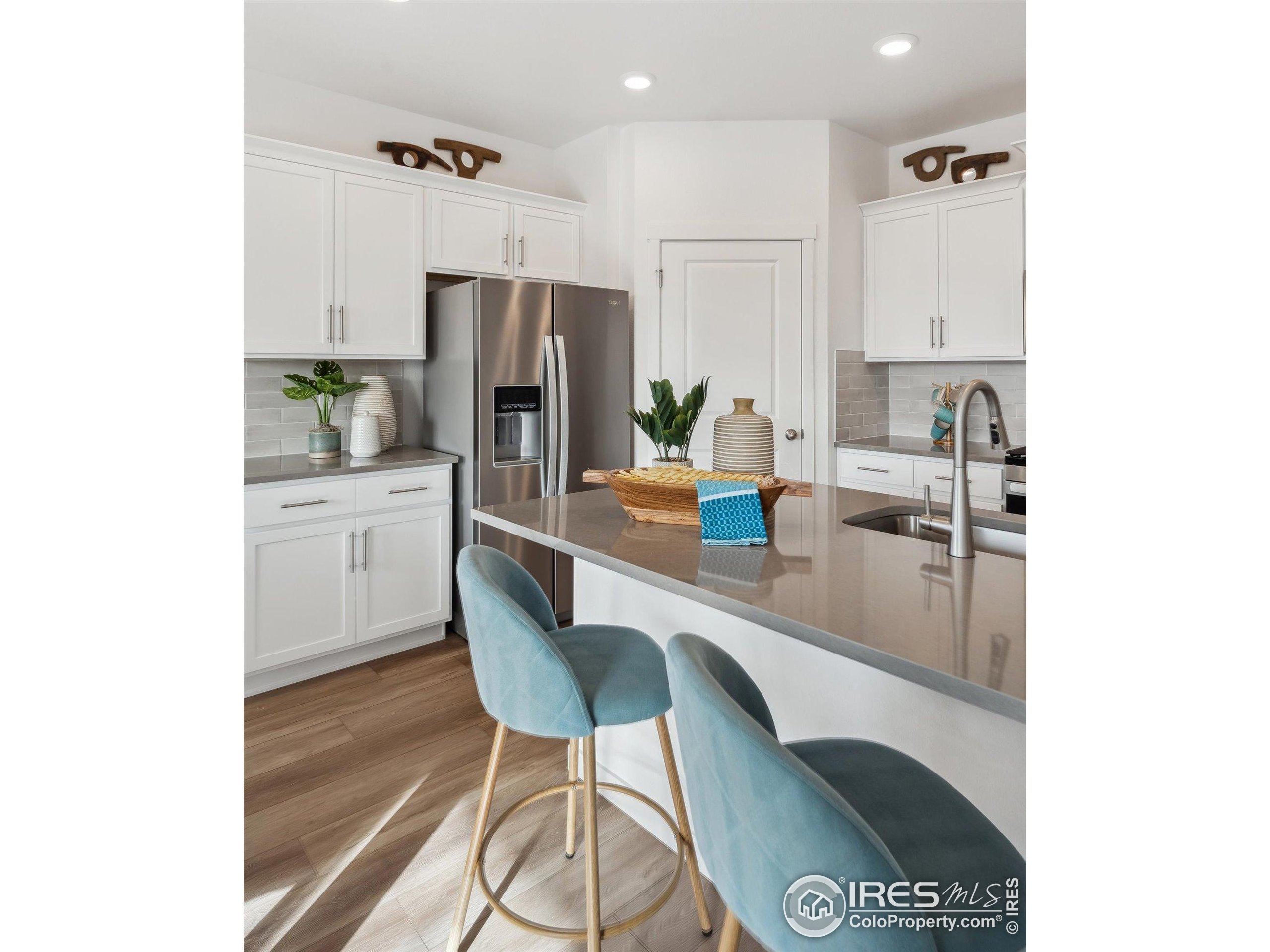 2207 Crosswind Street Fort Lupton, CO 80621 - Photo 7 of 26 a kitchen with a table chairs refrigerator and microwave