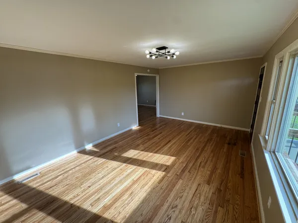 a view of a livingroom with wooden floor and a kitchen