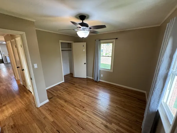 a view of empty room with wooden floor and fan
