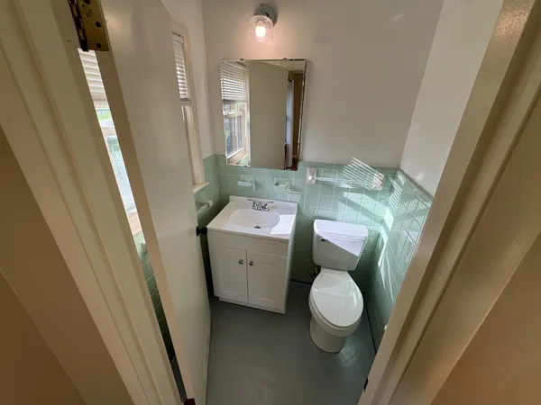 a bathroom with a toilet sink and mirror with window