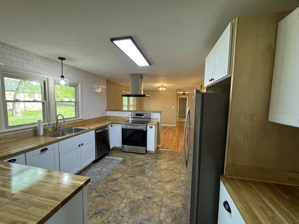 a large kitchen with a stove a sink dishwasher a refrigerator and wooden cabinets