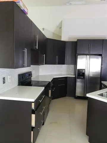 a kitchen with granite countertop a refrigerator and a stove top oven