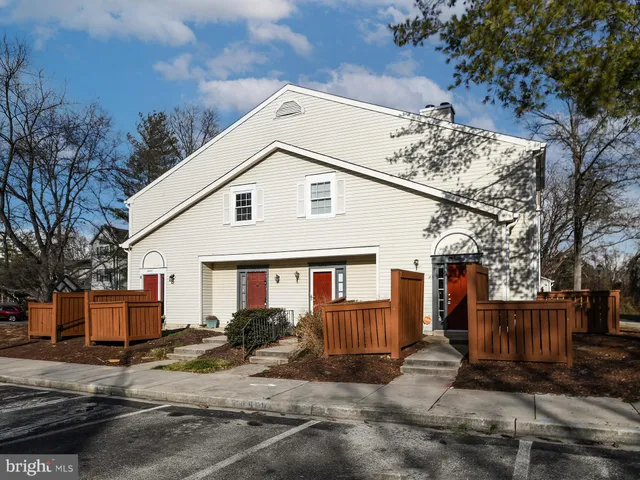a view of a white house with large windows and a table and chairs under an umbrella