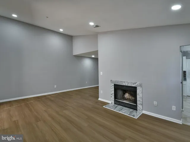 a view of an empty room with wooden floor and a fireplace