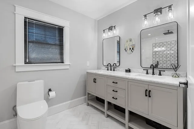 a bathroom with a double vanity sink a toilet and a mirror