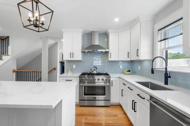 a kitchen with stainless steel appliances a white stove top oven a sink a window and cabinets