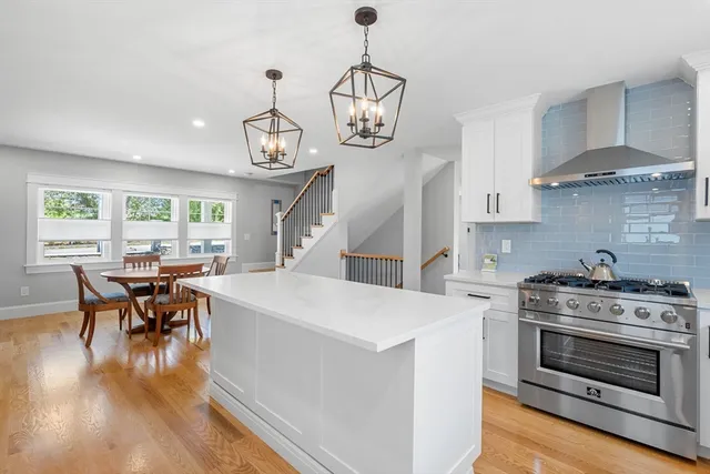 a kitchen with a stove a chandelier and wooden floor