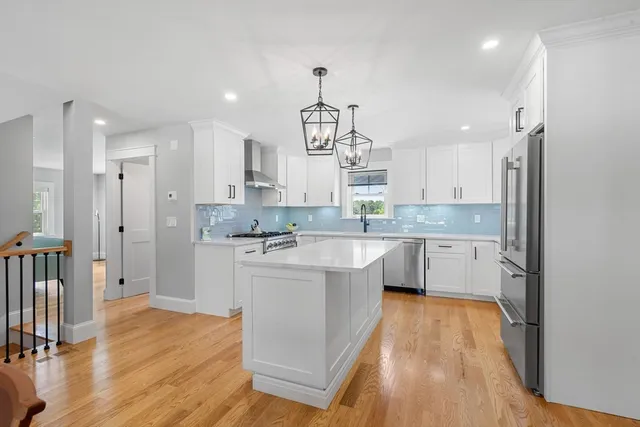 a large kitchen with a center island wooden floor stainless steel appliances and cabinets