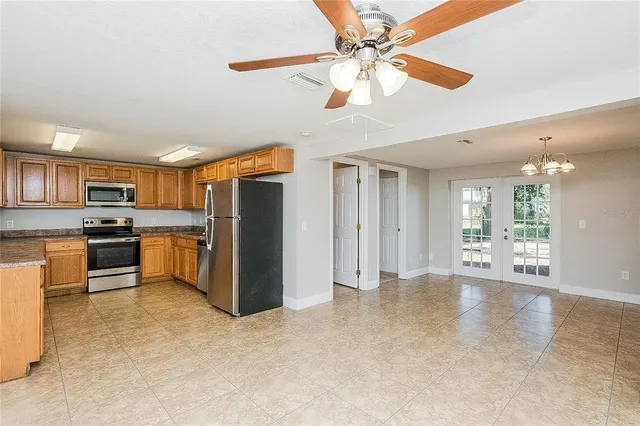 a view of a kitchen with stainless steel appliances kitchen island granite countertop a refrigerator and a stove top oven