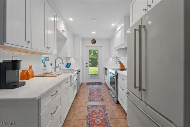 a kitchen with stainless steel appliances a refrigerator sink and white cabinets