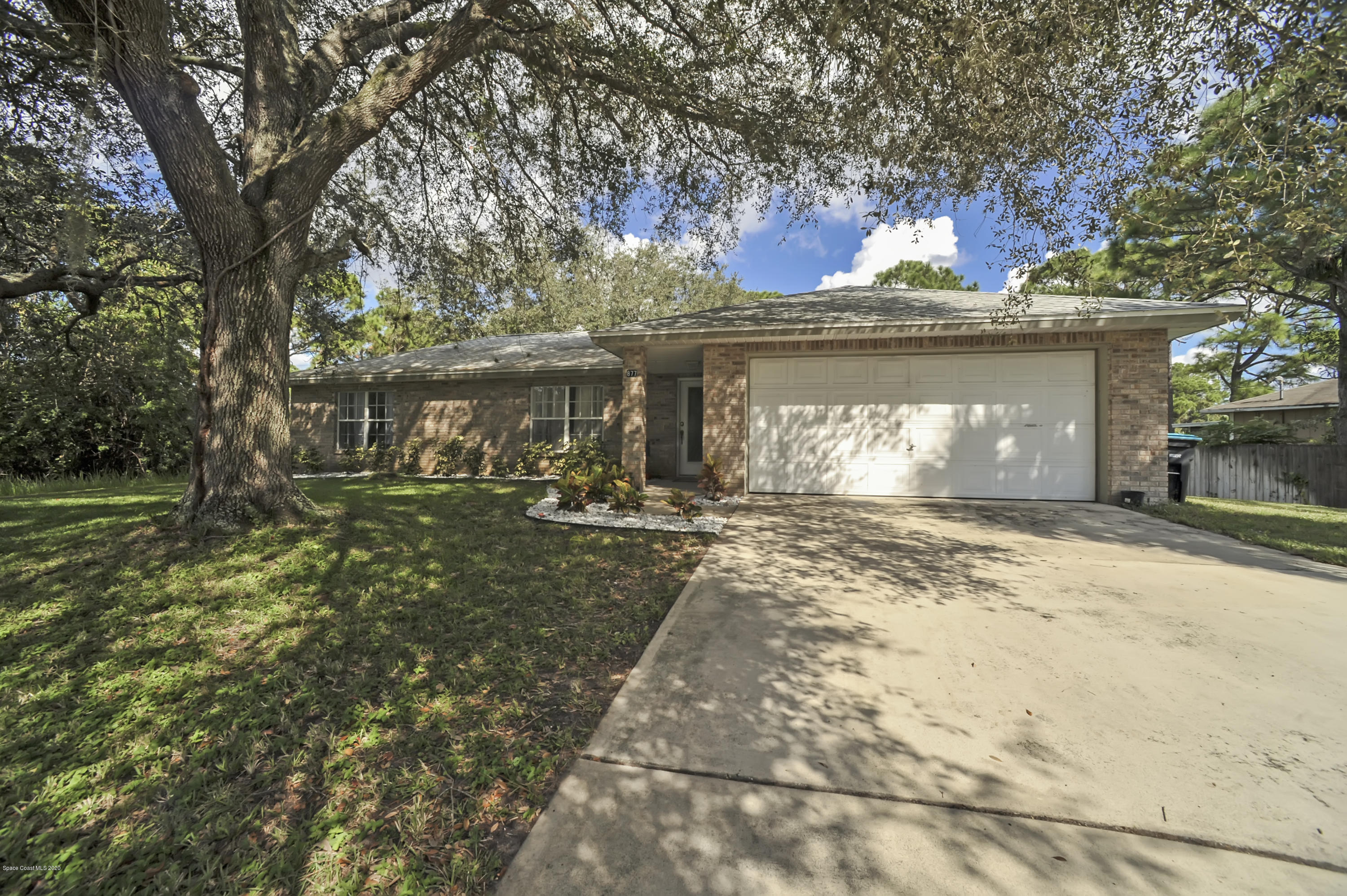 877 Walpole Road Southwest Palm Bay, FL 32908 - Photo 2 of 27 a front view of a house with a yard and a garage
