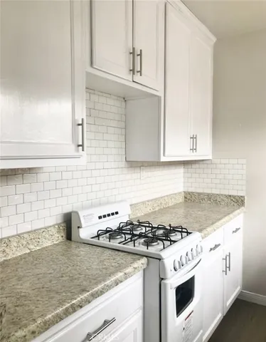a kitchen with granite countertop white cabinets and white appliances