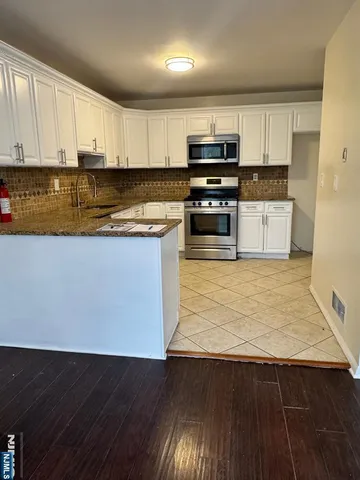 a kitchen with granite countertop a stove top oven a sink and cabinets
