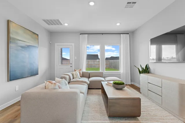 a living room with furniture and large windows with garden view