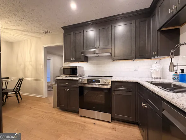 a kitchen with stainless steel appliances granite countertop wooden cabinets a stove top oven a sink and dishwasher