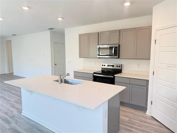 a kitchen with a sink a stove top oven and white kitchen island