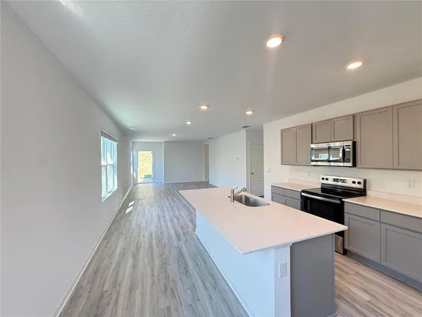 a large kitchen with kitchen island a stove a sink dishwasher and a refrigerator with wooden floor