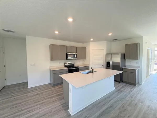 a large kitchen with kitchen island a sink a stove a refrigerator and a cabinets