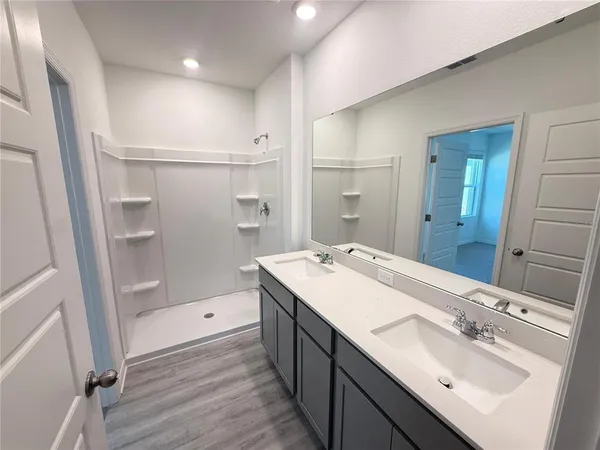 a bathroom with a double vanity sink mirror and shower
