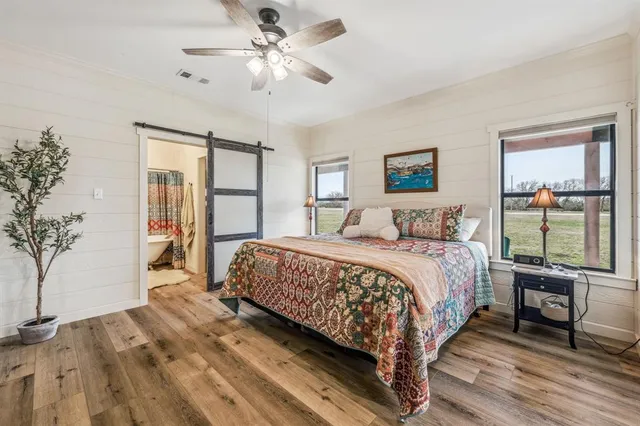 a bedroom with a large bed large windows with wooden floor