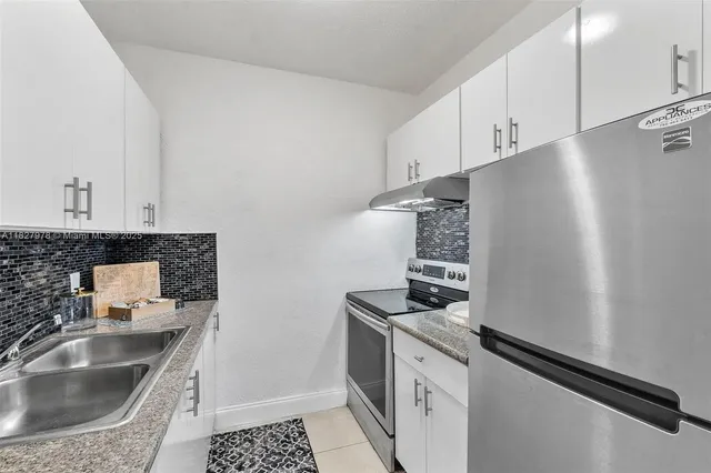 a kitchen with granite countertop a sink stove and refrigerator
