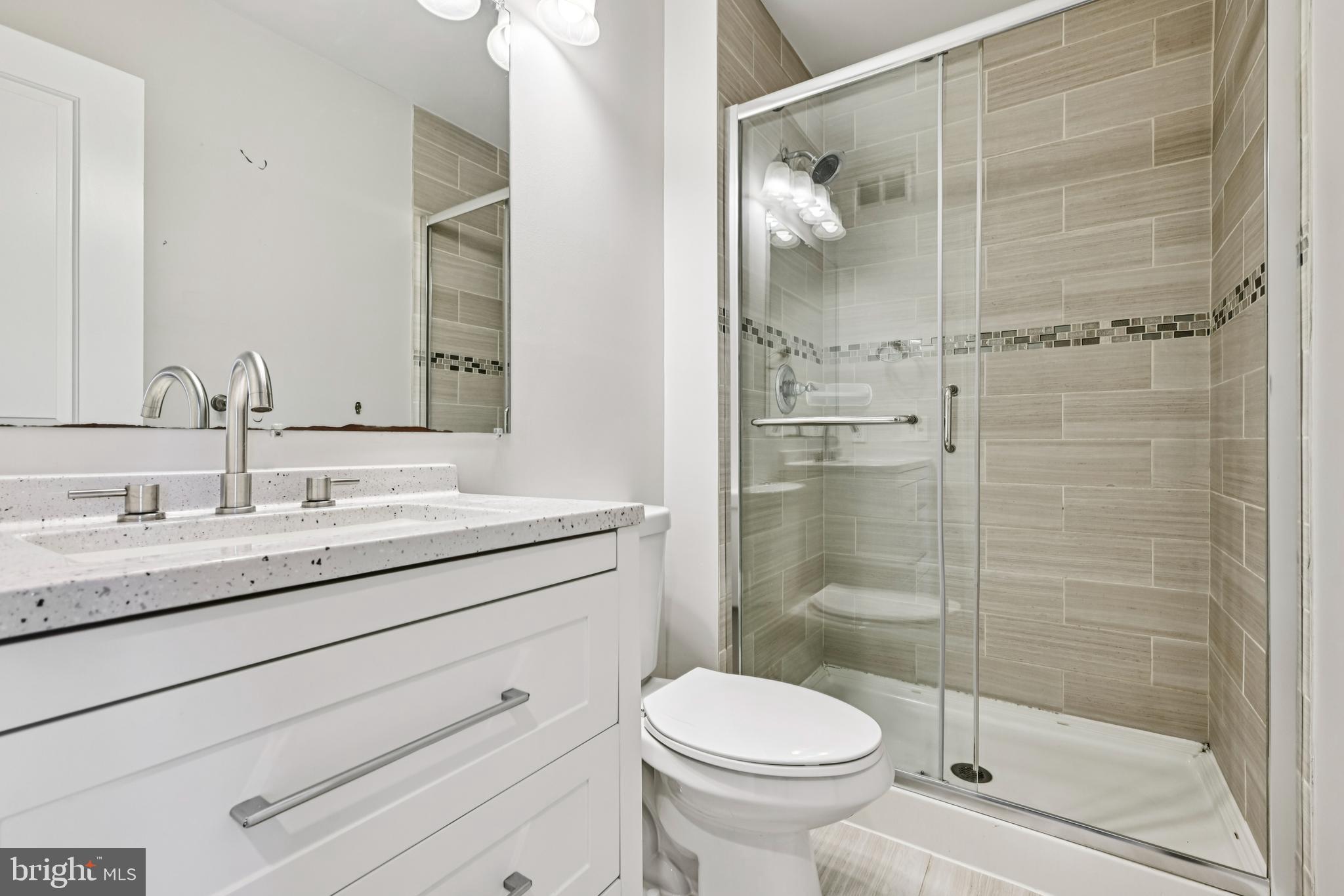 14901 Cleese Court, Unit 5CE Silver Spring, MD 20906 - Photo 19 of 25 a bathroom with a shower sink vanity mirror and toilet