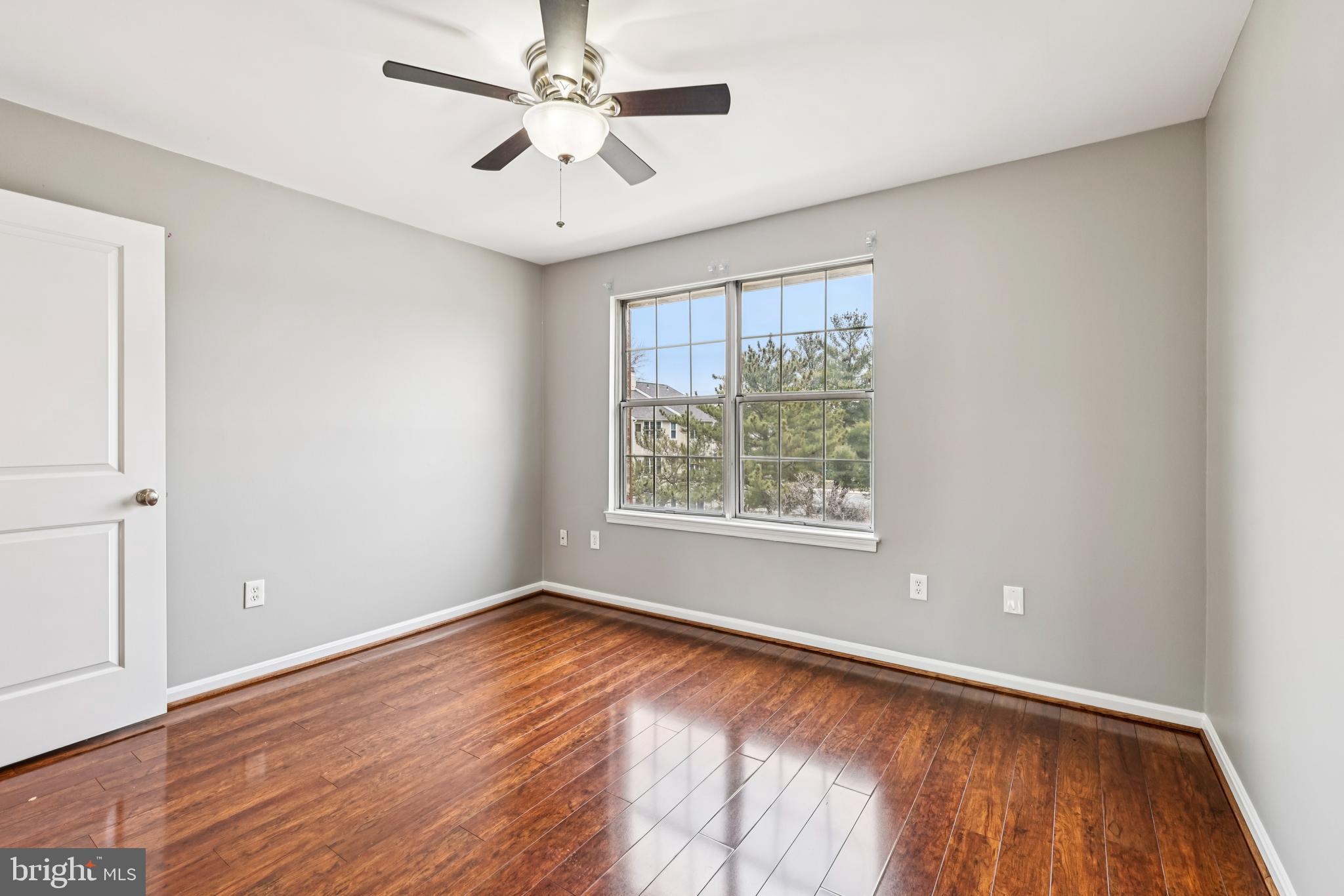 14901 Cleese Court, Unit 5CE Silver Spring, MD 20906 - Photo 23 of 25 an empty room with wooden floor chandelier fan and windows