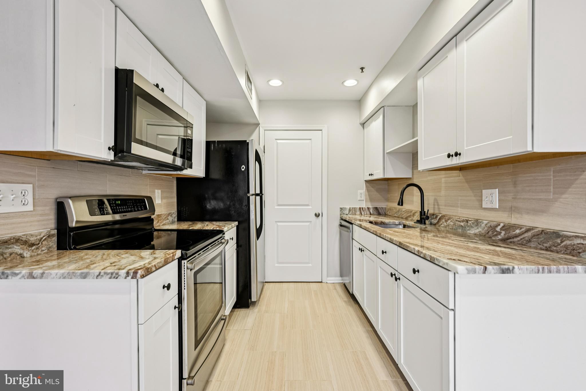 14901 Cleese Court, Unit 5CE Silver Spring, MD 20906 - Photo 7 of 25 a kitchen with stainless steel appliances a stove sink microwave and cabinets
