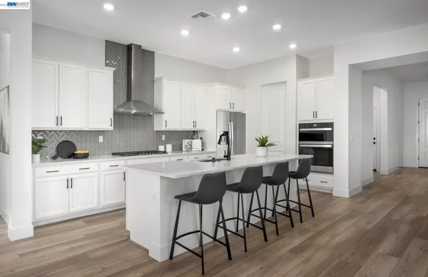 a kitchen with stainless steel appliances kitchen island granite countertop a table chairs sink and cabinets