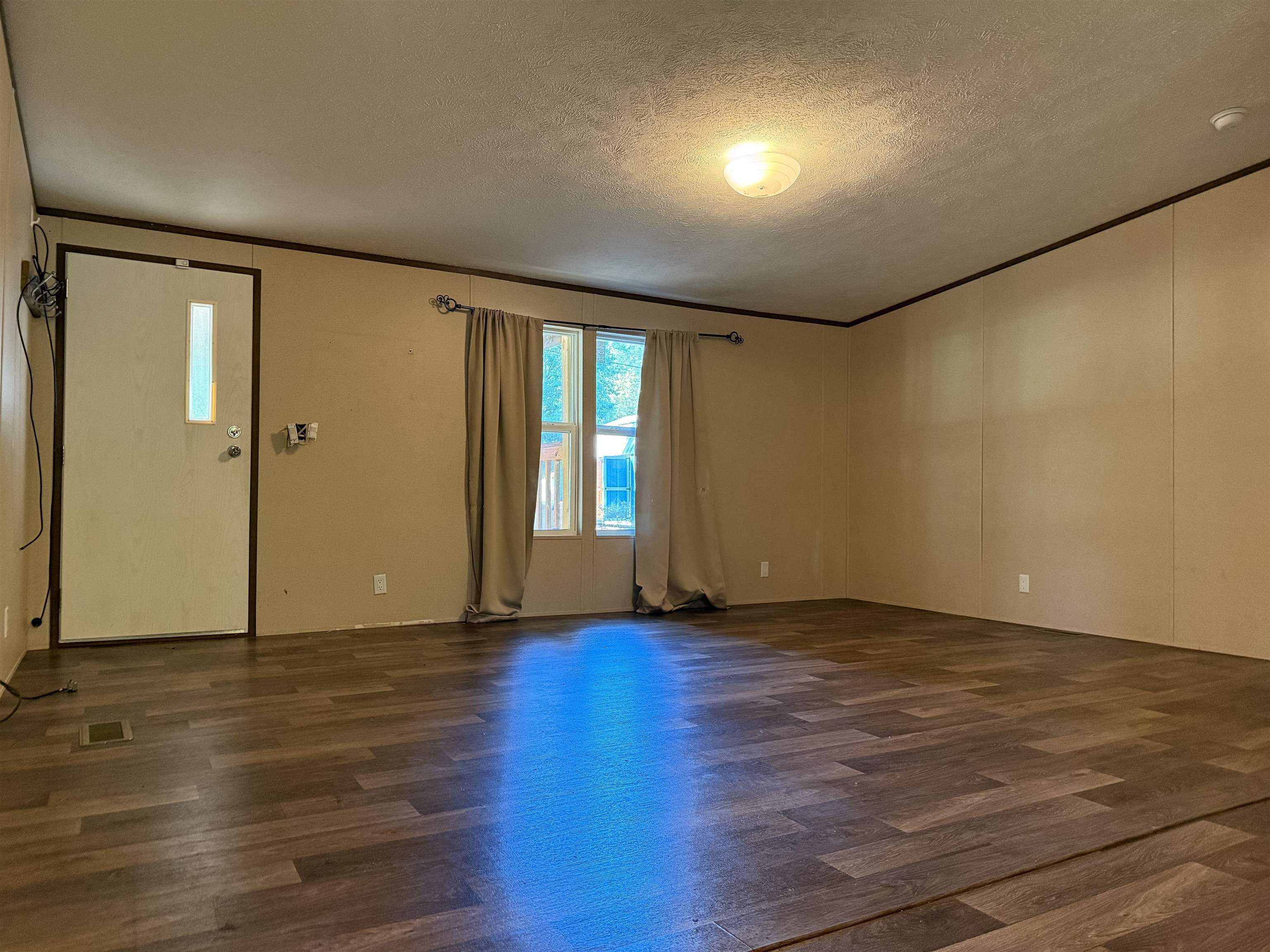 279 Travis Road Brewton, AL 36426 - Photo 7 of 17 Unfurnished living room with dark wood-type flooring, a textured ceiling, and ornamental molding