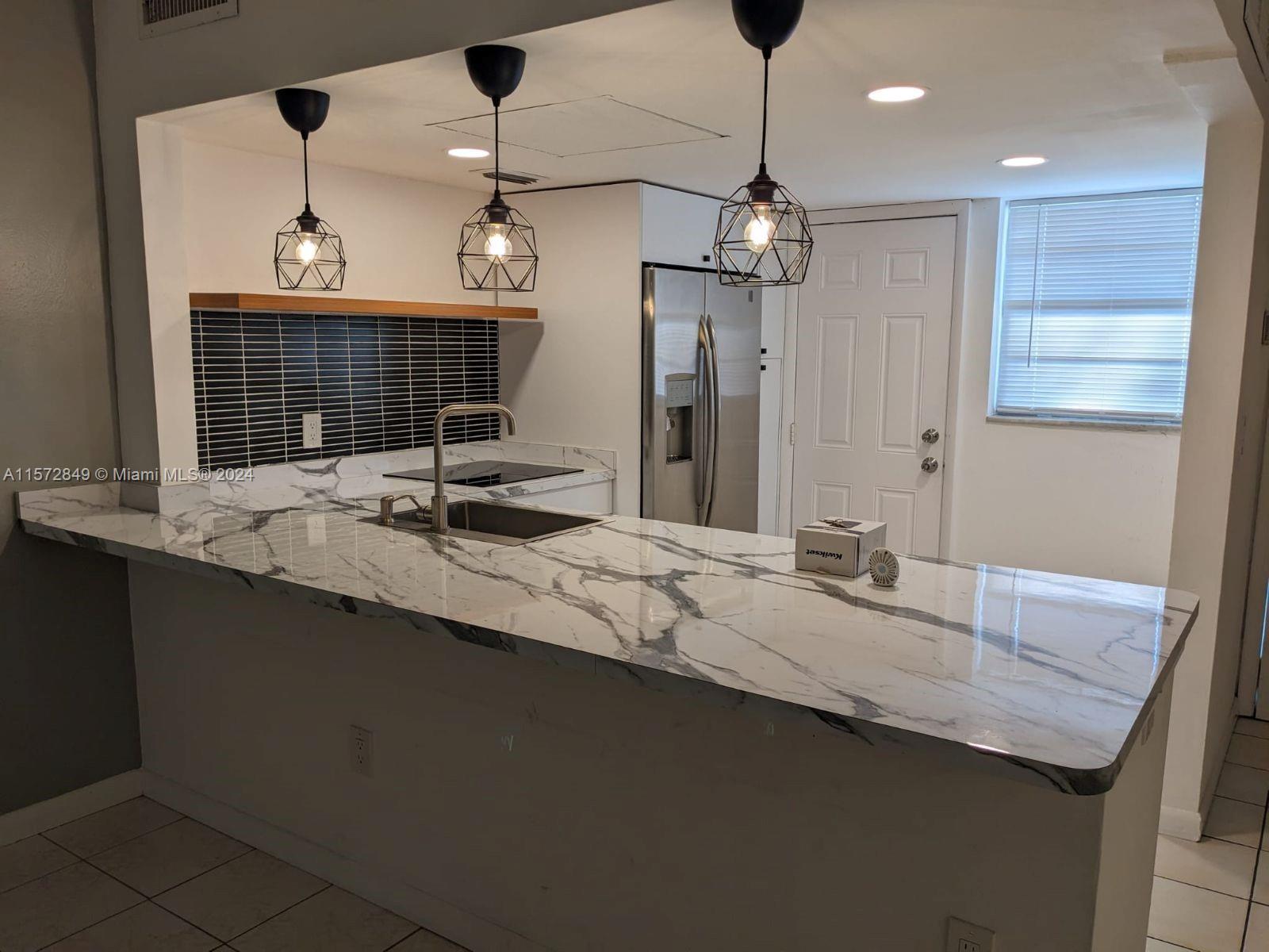 a kitchen with center island a sink stainless steel appliances and a chandelier