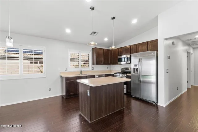 a kitchen with stainless steel appliances granite countertop a refrigerator a sink dishwasher a stove and a refrigerator with wooden floor