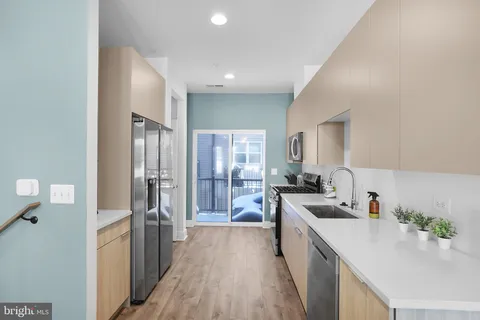 a large kitchen with a lot of counter space a sink and stainless steel appliances