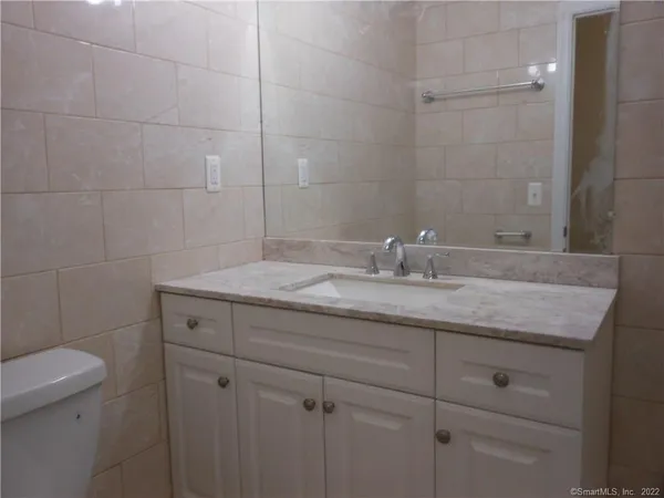 a bathroom with a granite countertop toilet and sink